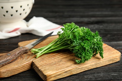 Photo of Cutting board with fresh green parsley and knife on wooden table
