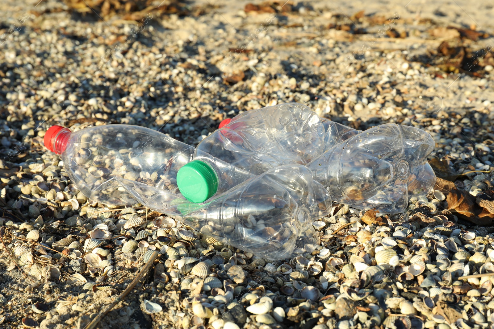 Photo of Used plastic bottles on sand outdoors. Environment pollution