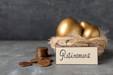 Photo of Many golden eggs, coins and card with word Retirement on grey table. Pension concept
