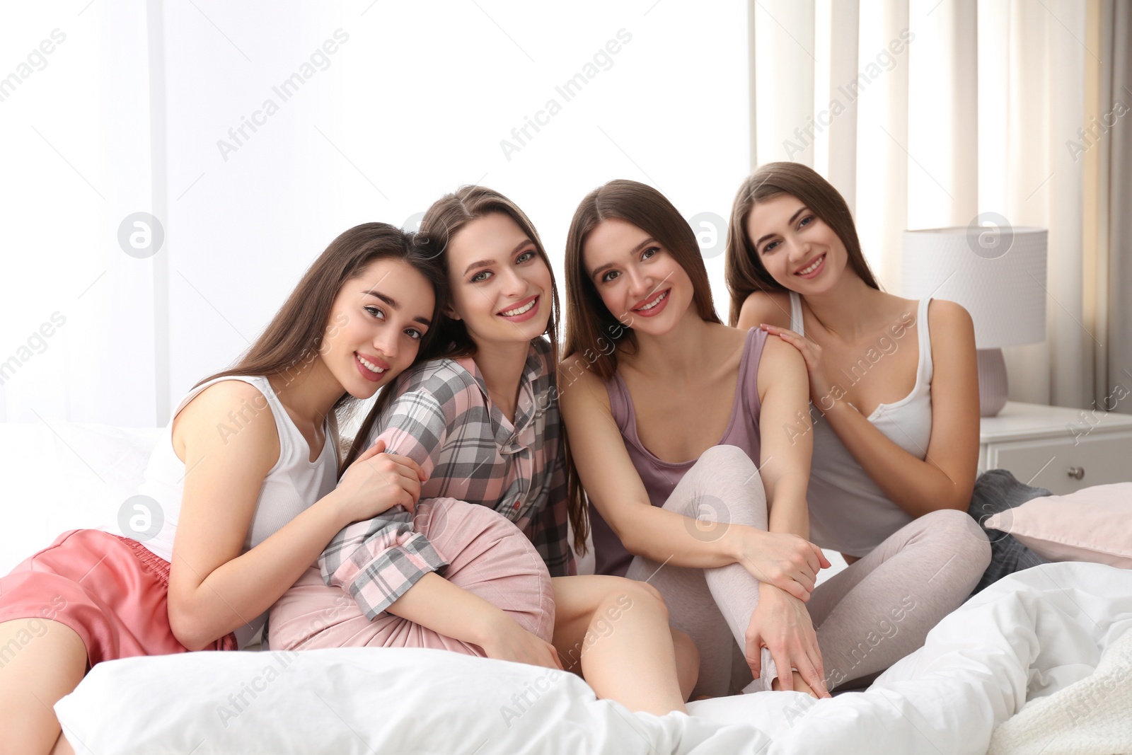 Photo of Beautiful young ladies on bed at pamper party. Woman's Day