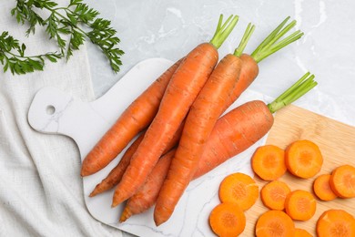 Photo of Whole and sliced fresh ripe juicy carrots on light grey marble table, flat lay