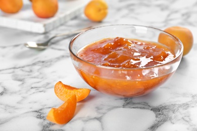 Photo of Bowl with tasty apricot jam on table