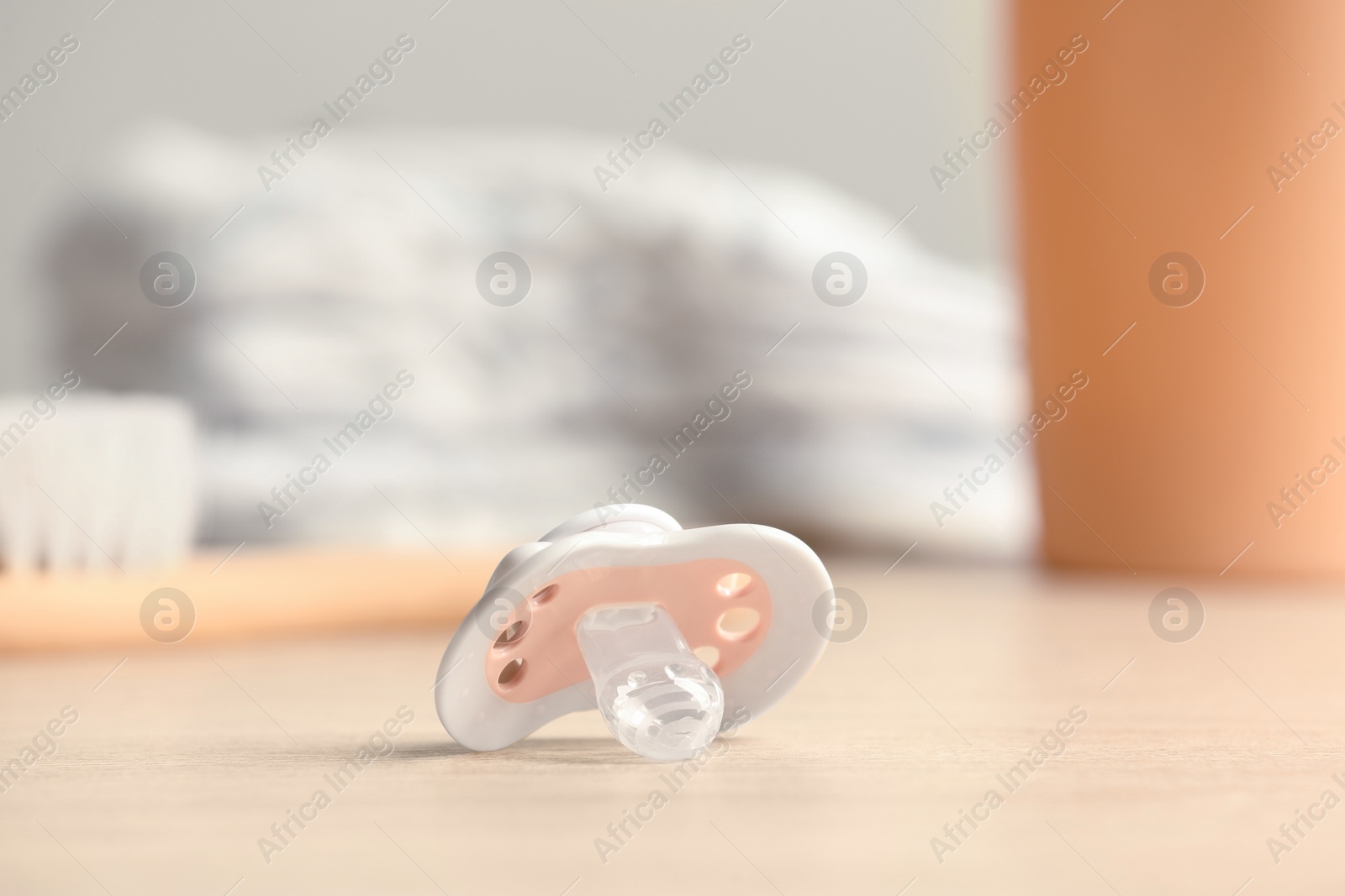 Photo of Baby pacifiers on beige table against blurred background, space for text