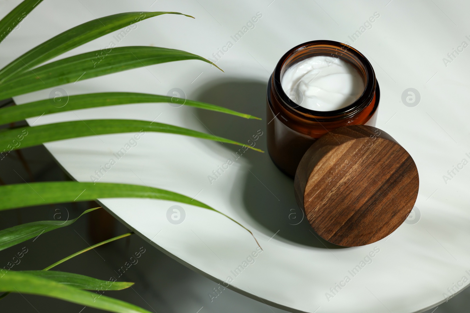 Photo of Open jar of cosmetic cream on white table