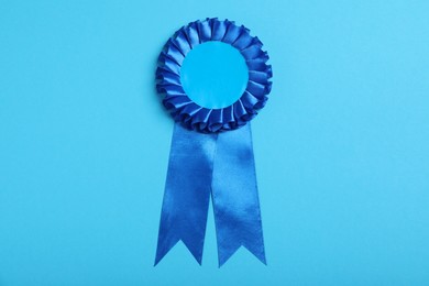 Photo of Blue award ribbon on turquoise background, top view