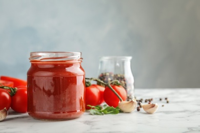 Composition with jar of tasty tomato sauce on table against grey background. Space for text