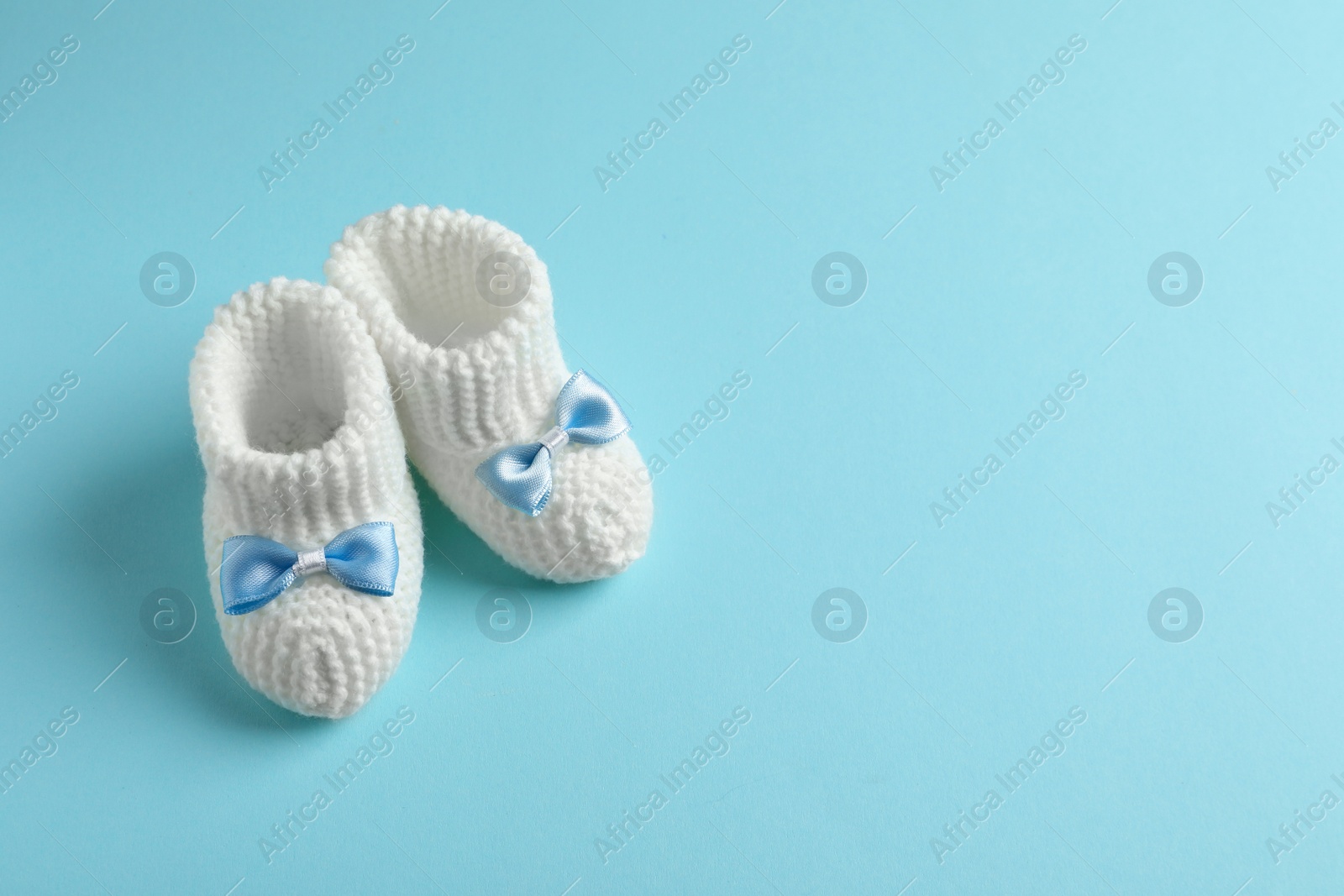 Photo of Handmade baby booties on color background. Space for text