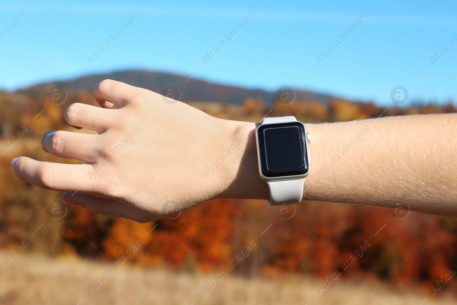 Photo of Woman checking smart watch with blank screen in wilderness, closeup