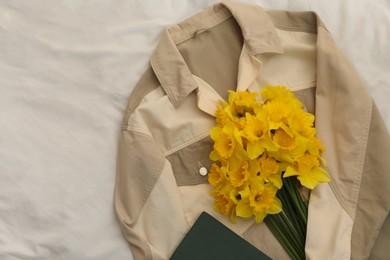 Beautiful daffodils, shirt and book on bed, flat lay. Space for text
