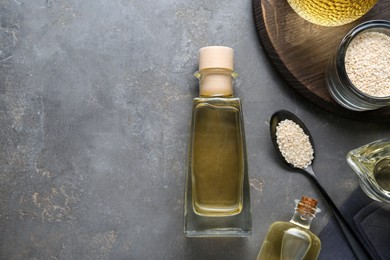 Fresh sesame oil and seeds on grey table, flat lay. Space for text