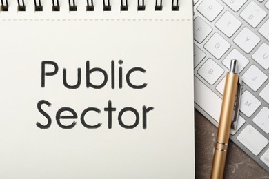 Image of Notebook with phrase PUBLIC SECTOR and keyboard on table, flat lay