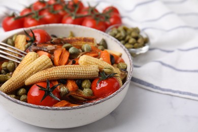 Photo of Tasty roasted baby corn with tomatoes and capers on white marble table, closeup