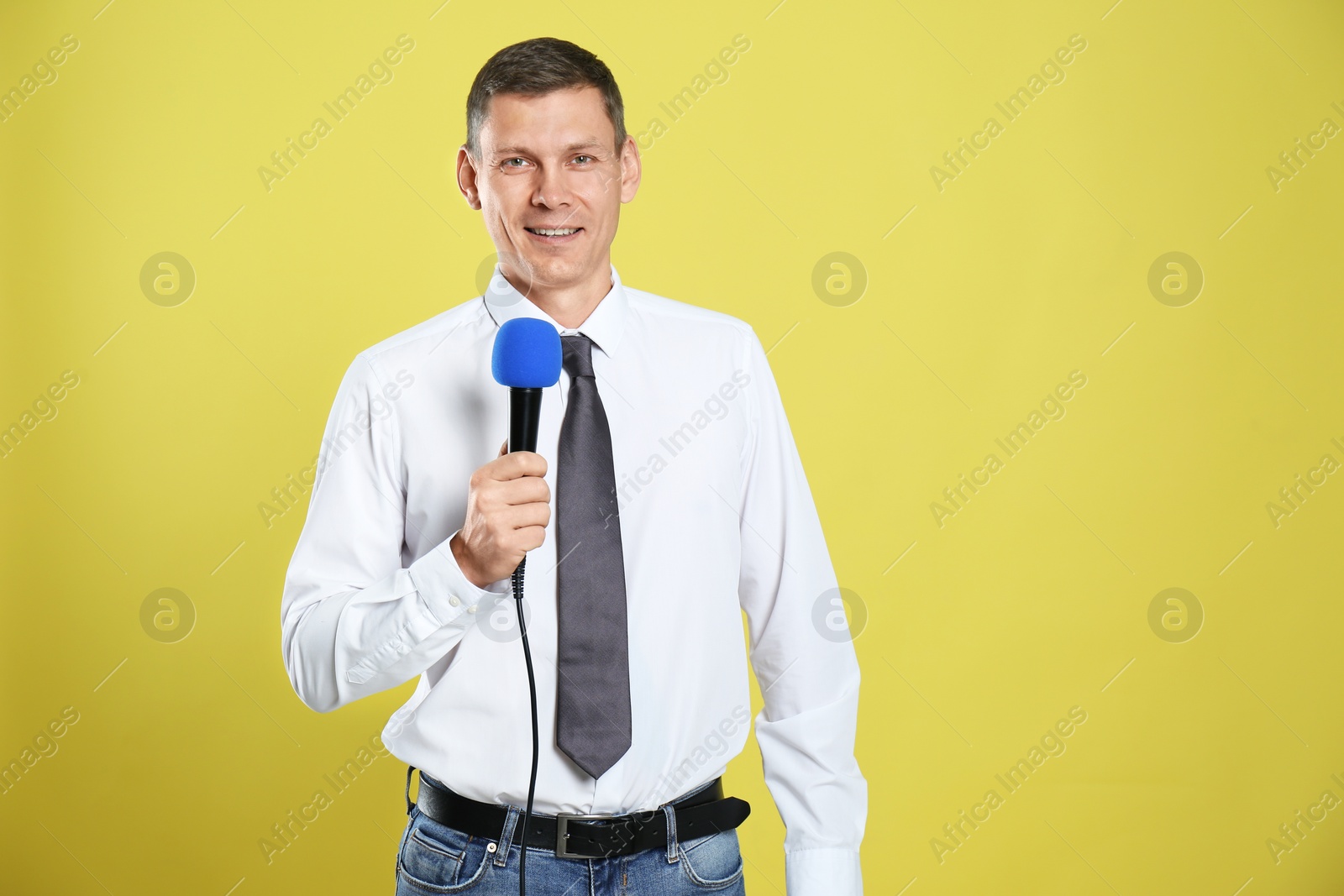 Photo of Male journalist with microphone on yellow background