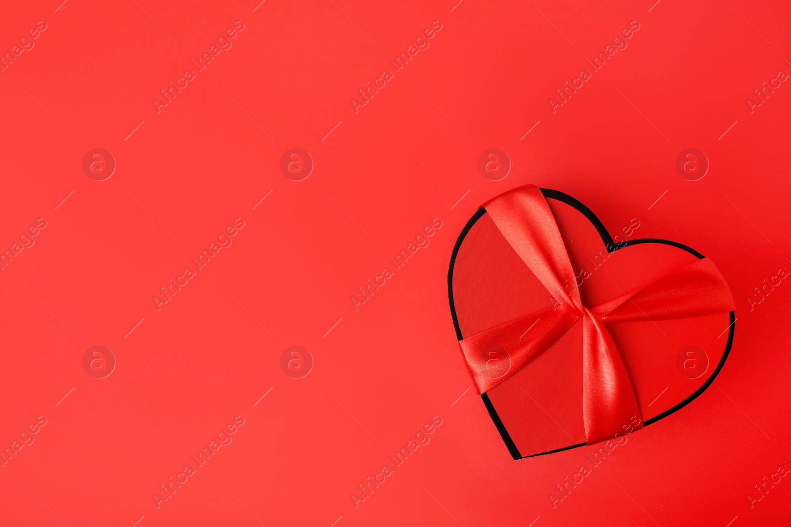 Photo of Beautiful heart shaped gift box on red background, top view. Space for text