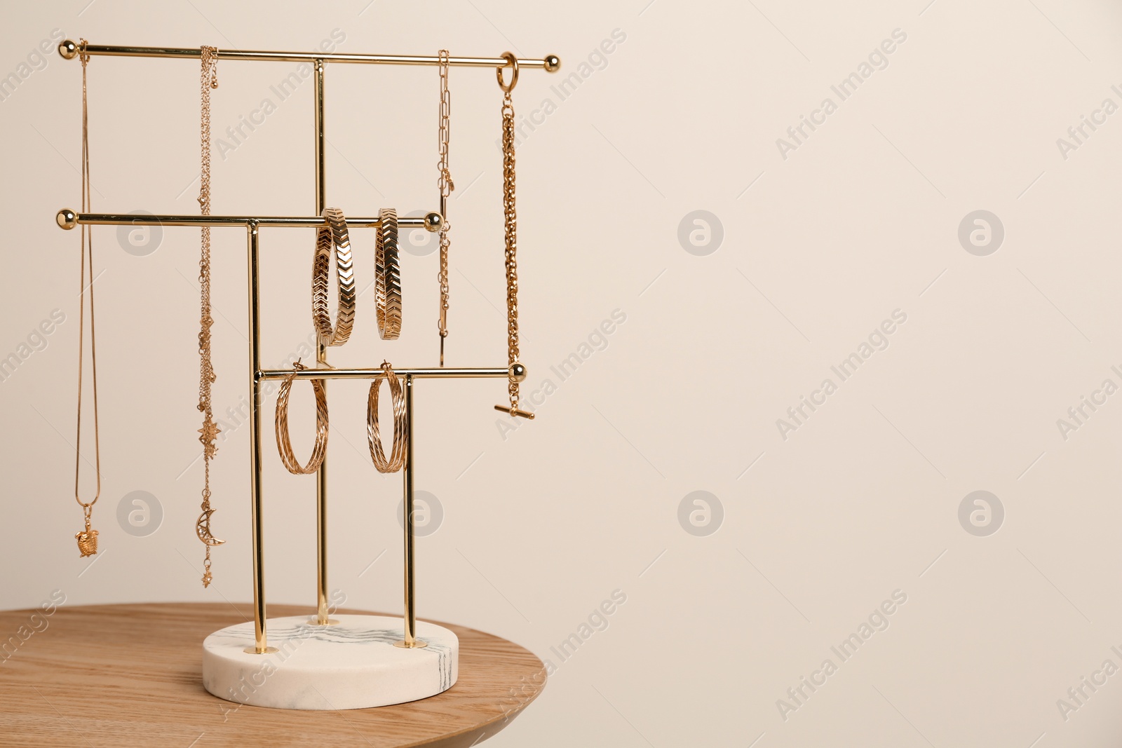 Photo of Holder with set of luxurious jewelry on wooden table. Space for text