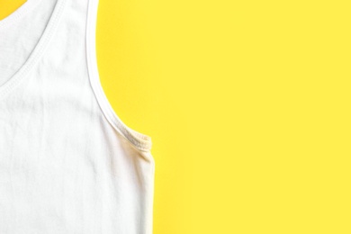 Undershirt with deodorant stain on yellow background, top view. Space for text