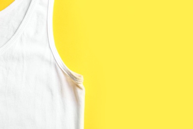 Photo of Undershirt with deodorant stain on yellow background, top view. Space for text