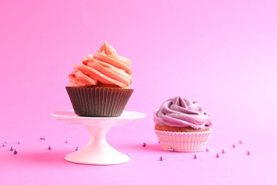 Delicious cupcakes with bright cream and sprinkles on pink background. Space for text