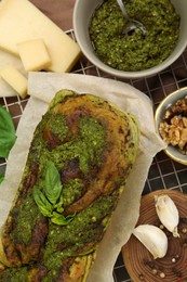 Photo of Freshly baked pesto bread with ingredients on table, flat lay