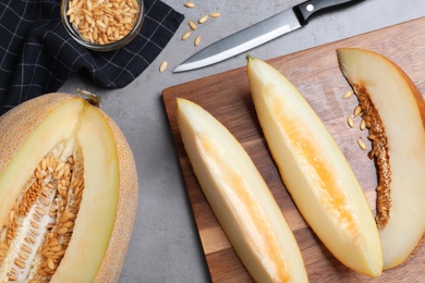 Photo of Slices of delicious honey melon on grey table, flat lay