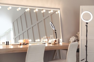 Modern mirror with light bulbs on dressing table in makeup room