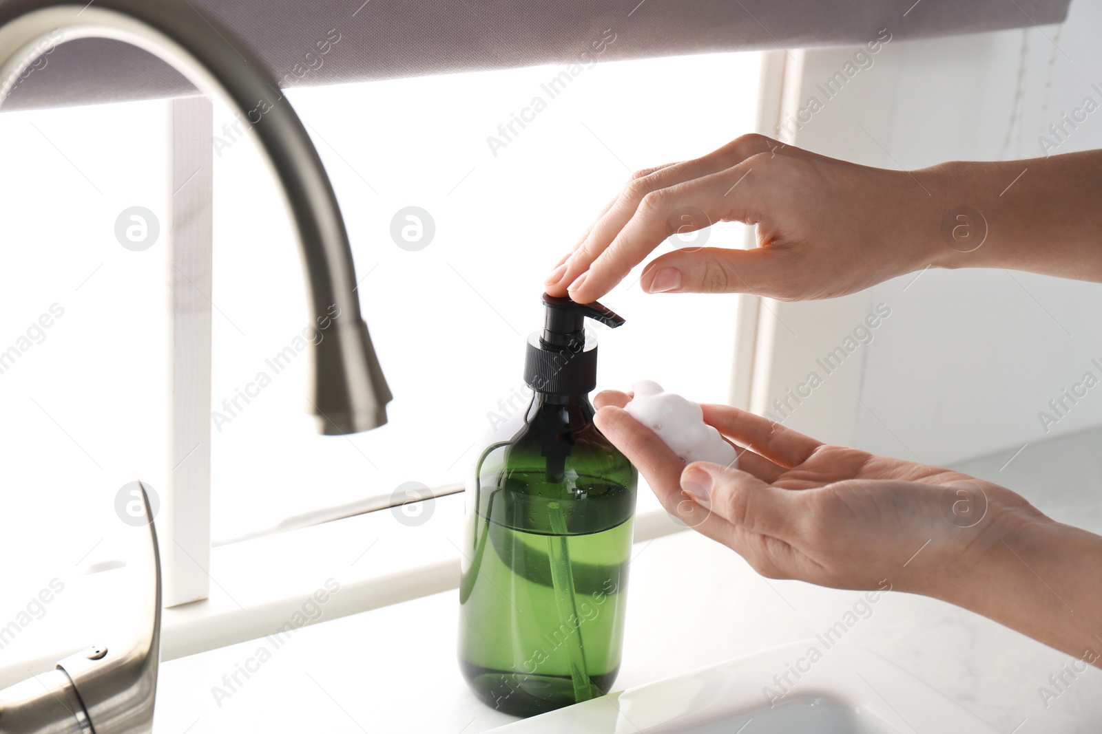 Photo of Woman using soap dispenser in kitchen, closeup