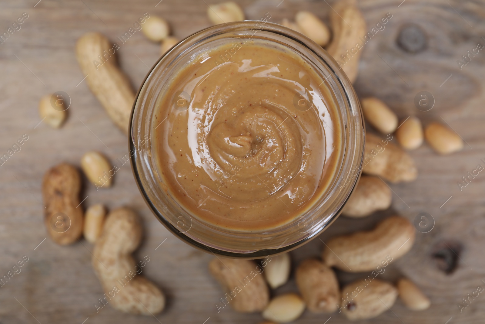 Photo of Tasty peanut nut paste in jar on table, top view