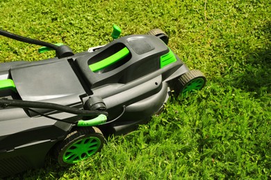 Cutting green grass with lawn mower in garden