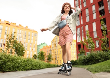 Beautiful young woman with roller skates having fun outdoors, space for text