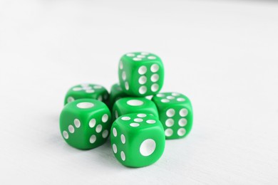 Photo of Many green game dices on white wooden table, closeup