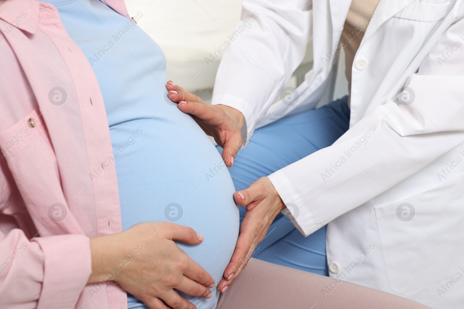 Photo of Pregnancy checkup. Doctor examining patient's tummy in clinic, closeup