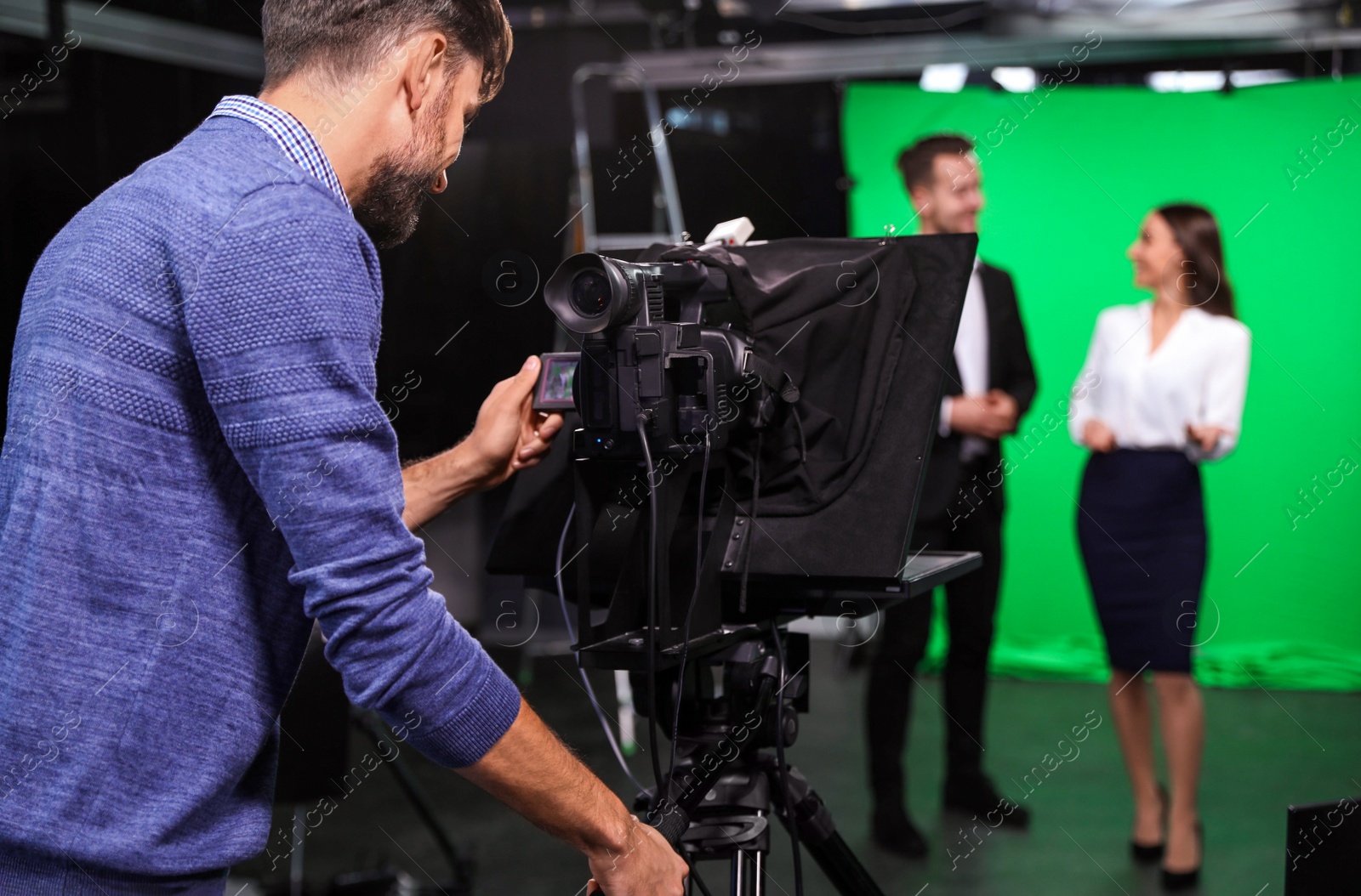 Photo of Presenters and video camera operator working in studio. News broadcasting