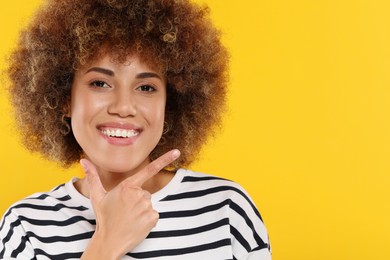 Photo of Woman showing her clean teeth on yellow background, space for text
