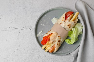 Photo of Delicious pita wrap with sausage, french fries and vegetables on light gray table, top view. Space for text