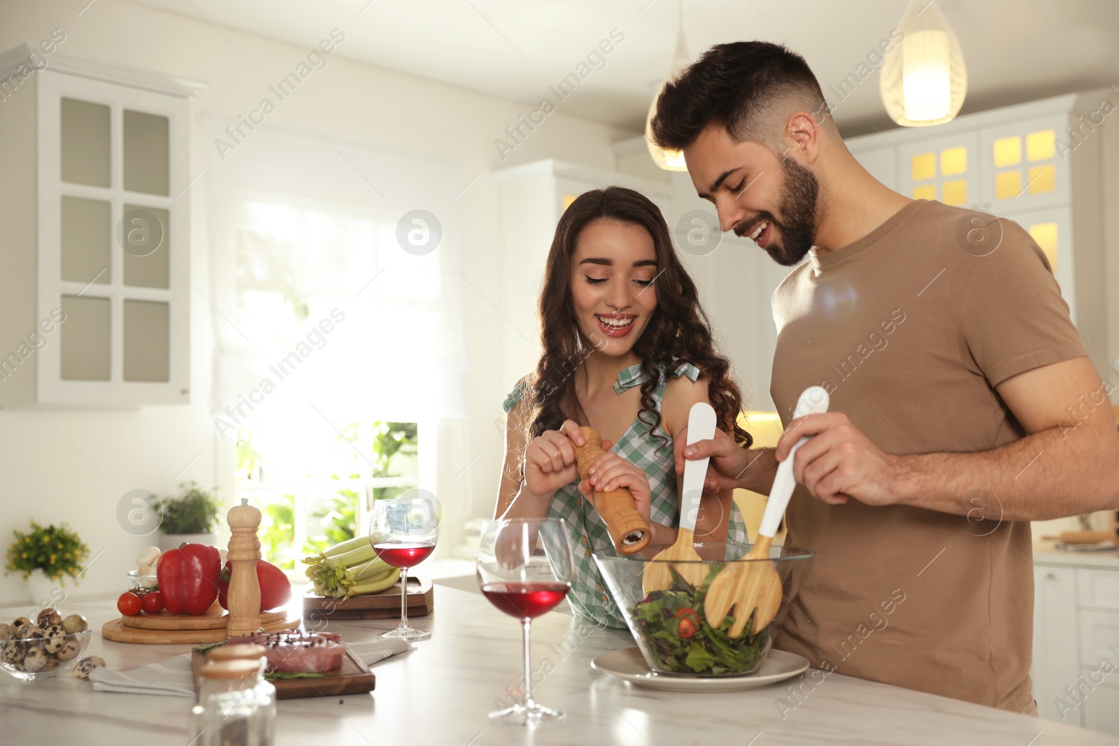 Photo of Lovely young couple cooking salad together in kitchen