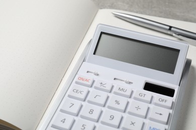 Photo of Calculator and pen on open notebook, closeup