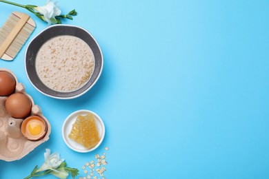 Photo of Homemade hair mask in bowl, fresh ingredients and bamboo comb on light blue background, flat lay. Space for text