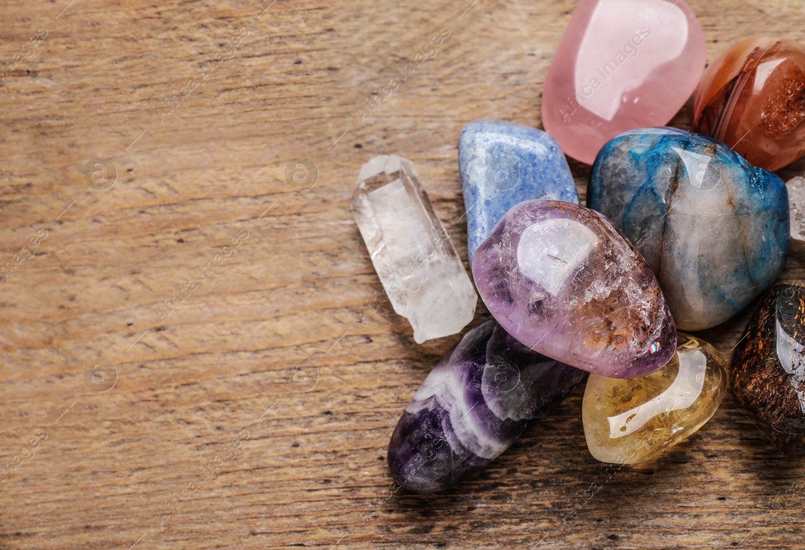 Photo of Flat lay composition with different gemstones on wooden table, space for text