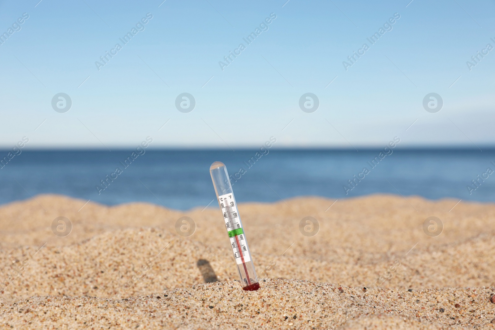 Photo of Weather thermometer in sand near sea, space for text