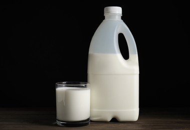 Photo of Gallon bottle and glass of milk on wooden table