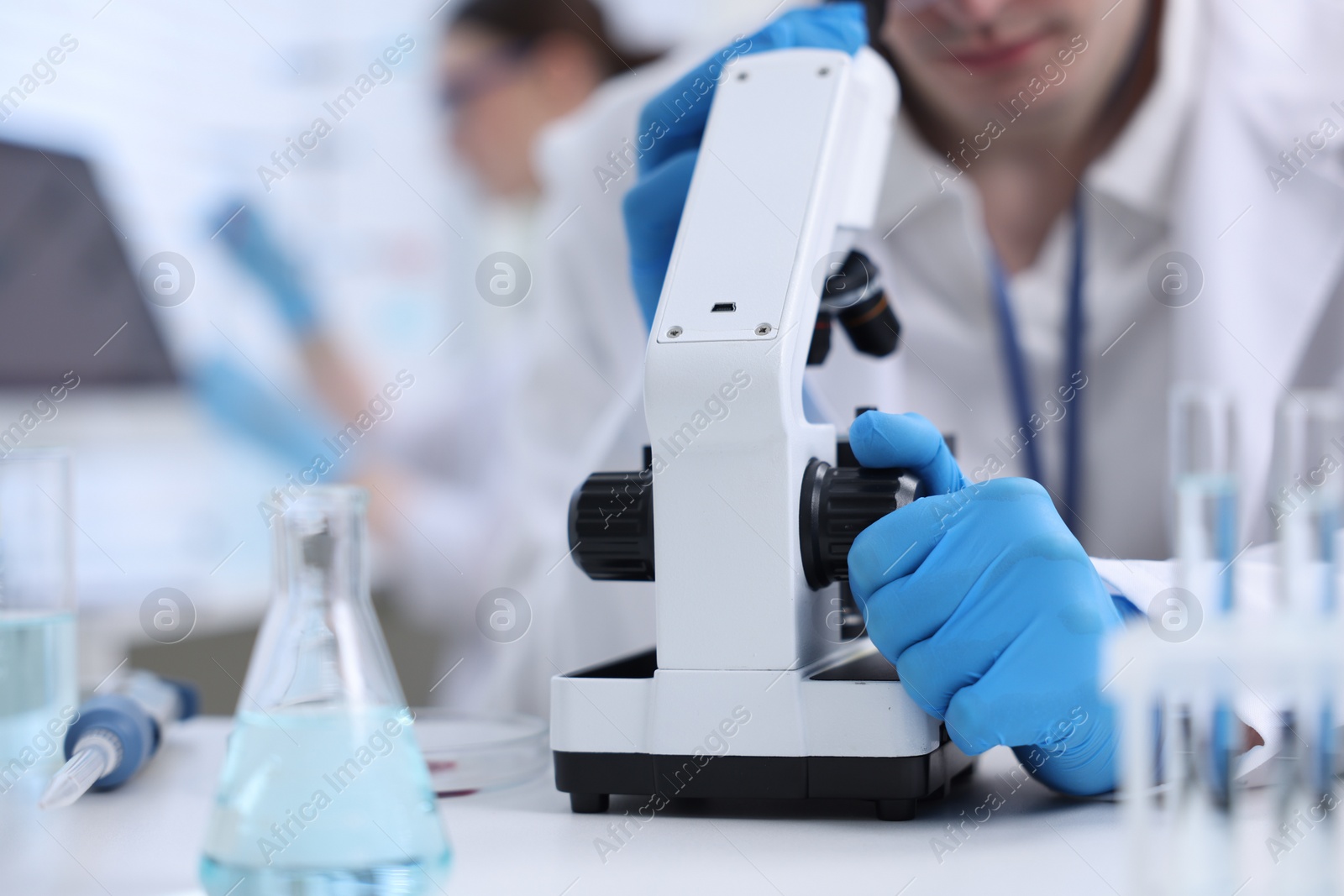 Photo of Scientist working with microscope in laboratory, closeup