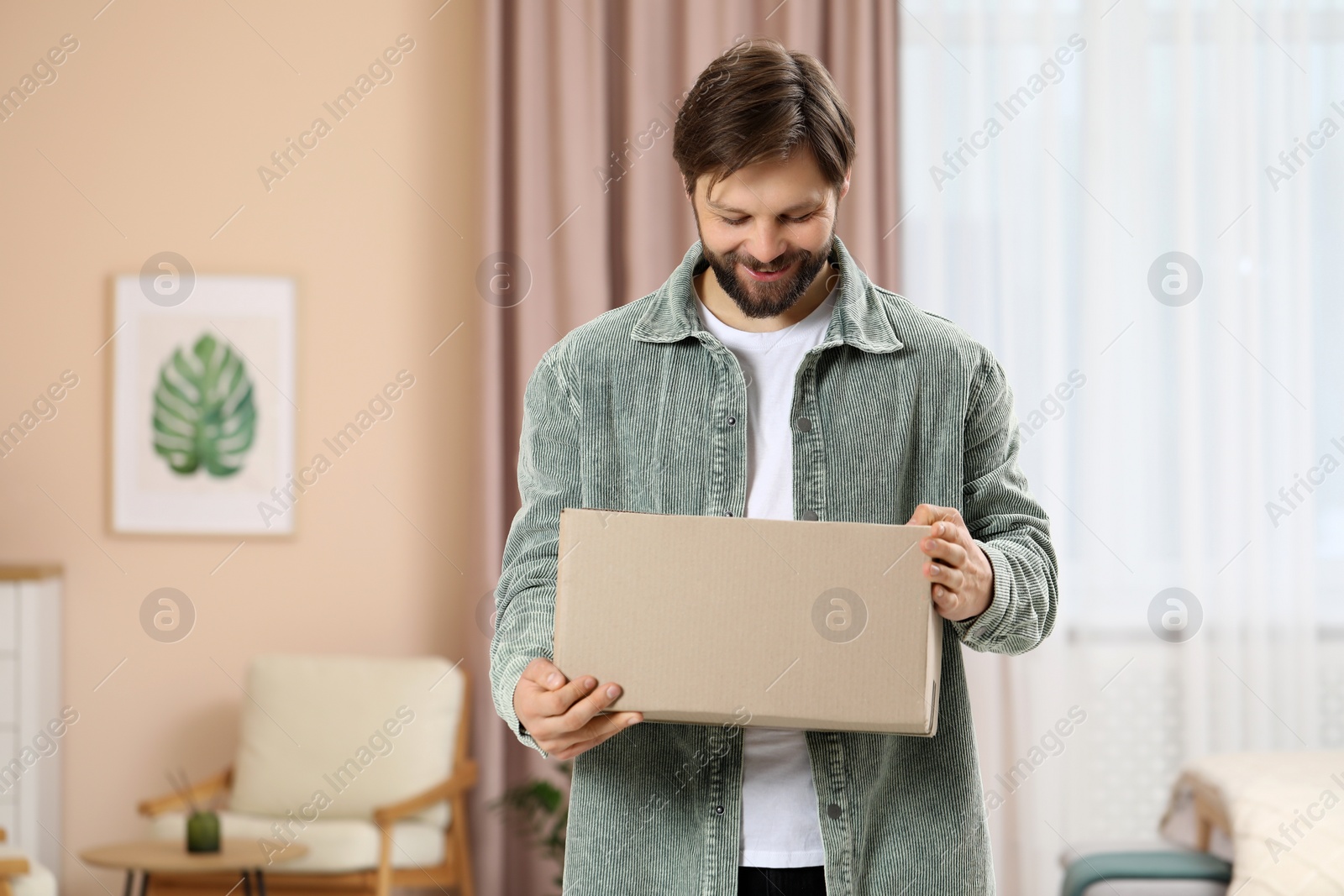 Photo of Man with parcel at home. Internet shopping