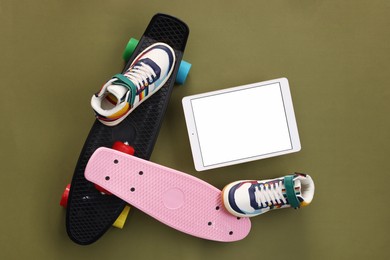 Photo of Modern tablet, skateboards and shoes on olive background, flat lay. Space for text