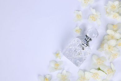 Photo of Aromatic perfume in bottle and beautiful jasmine flowers on white background, flat lay. Space for text