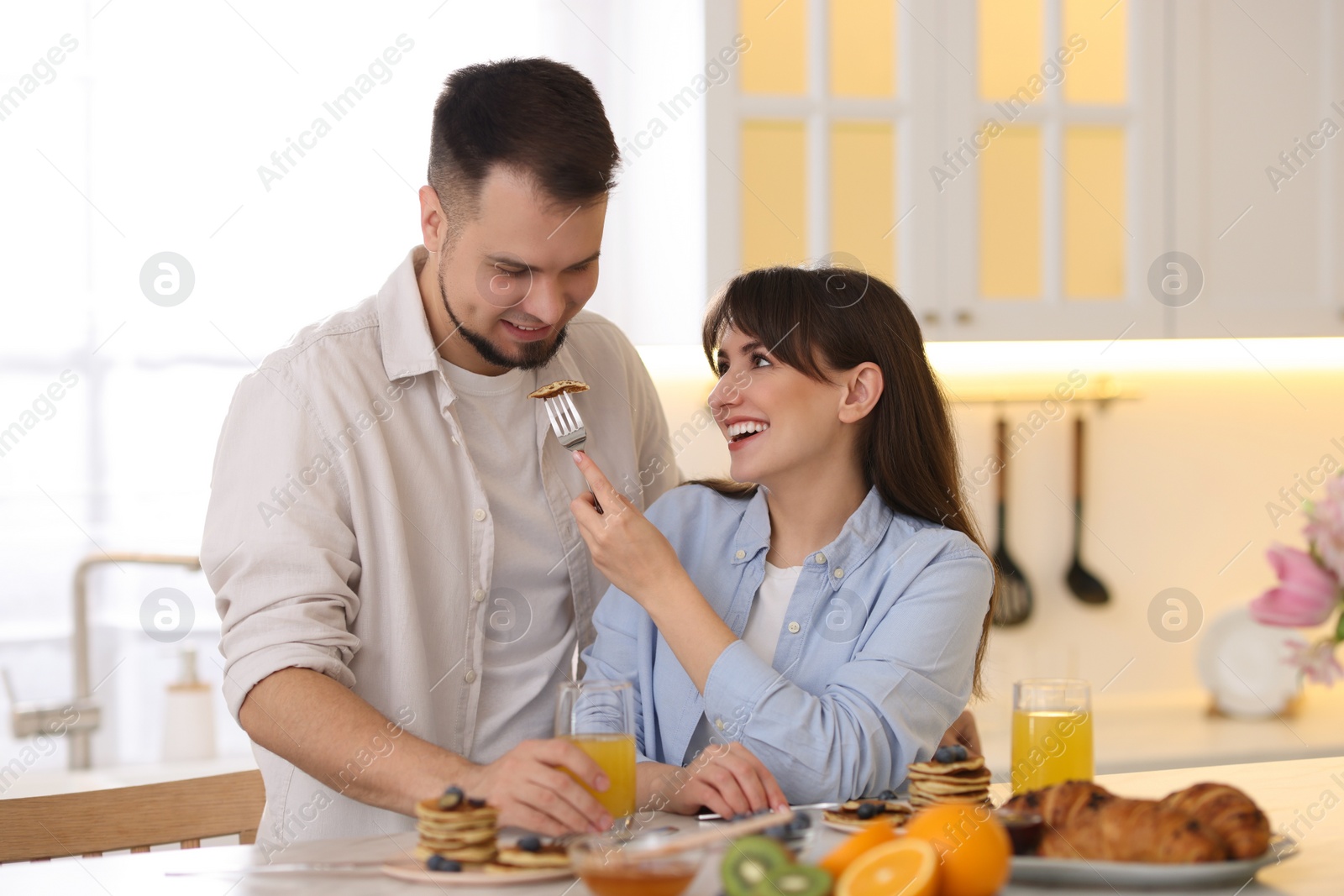 Photo of Tasty breakfast. Happy wife feeding her husband at home