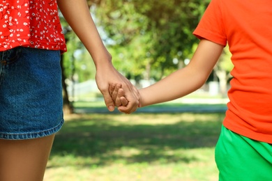 Photo of Little boy and his mother holding hands outdoors, closeup. Family weekend