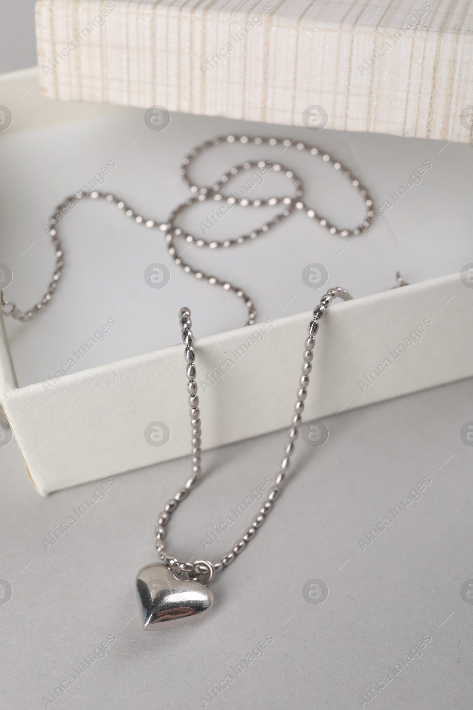 Photo of Metal chain with pendant and box on light table. Luxury jewelry