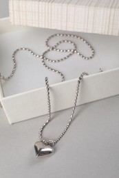 Metal chain with pendant and box on light table. Luxury jewelry