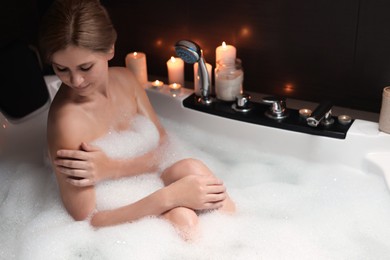 Beautiful woman taking bubble bath indoors. Romantic atmosphere