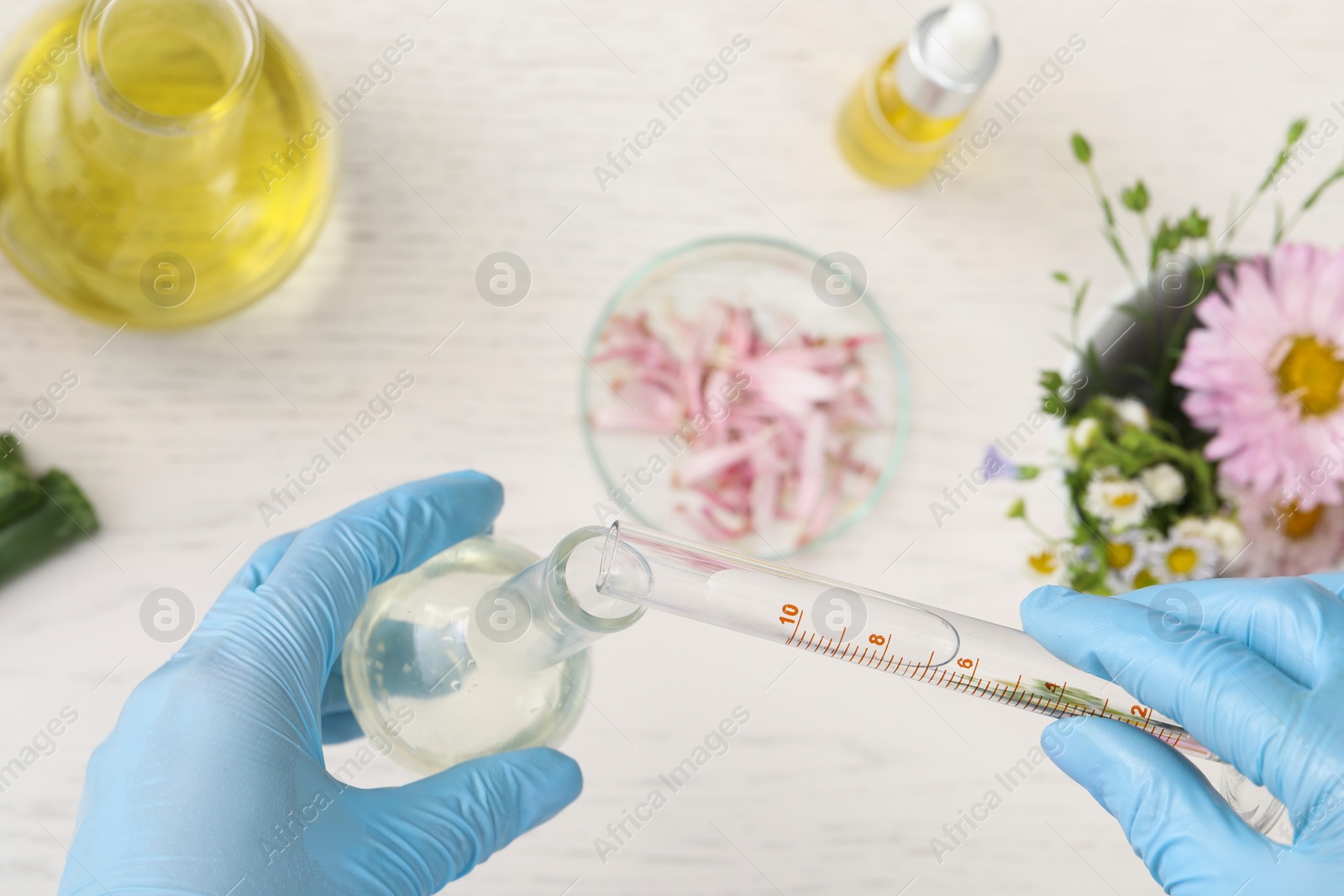 Photo of Scientist developing cosmetic oil at white wooden table, top view